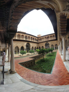 Blick in einen andalusischen Innenhof mit Gartenanlage, Säulengang und Hufeisenbögen