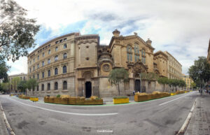 Panoramaaufnahme einer Kirche mit neoromanischer Fassade und benachbarten Stadtgebäuden