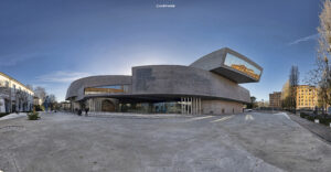 Panoramische Außenansicht des MAXXI Museums in Rom, ein modernes Gebäude aus Beton mit einzigartigen Formen und großen Glasfronten, unter strahlend blauem Himmel.