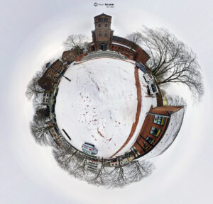 360°-Panoramablick auf verschneite Backsteingebäude und einen zentralen Turm mit Schriftzug „Yousif Karyakes Architect“ unter kahlen Bäumen.